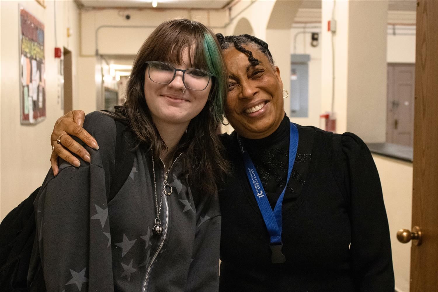 Student and teacher pose with arms wrapped around the other
